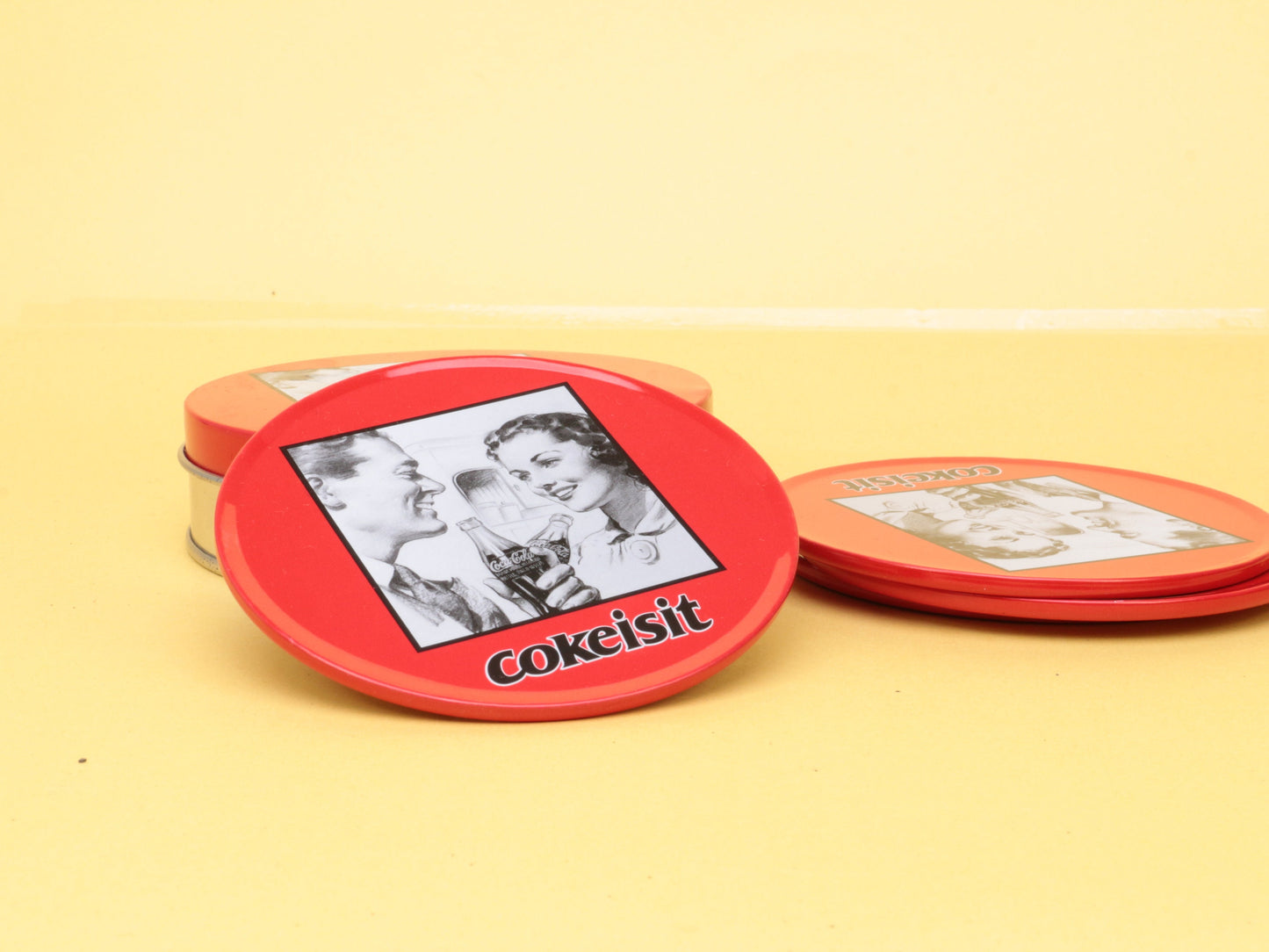 Vintage Coca Cola Set van 4 metalen onderzetters in een bewaarblik, met tekst CokeItIs