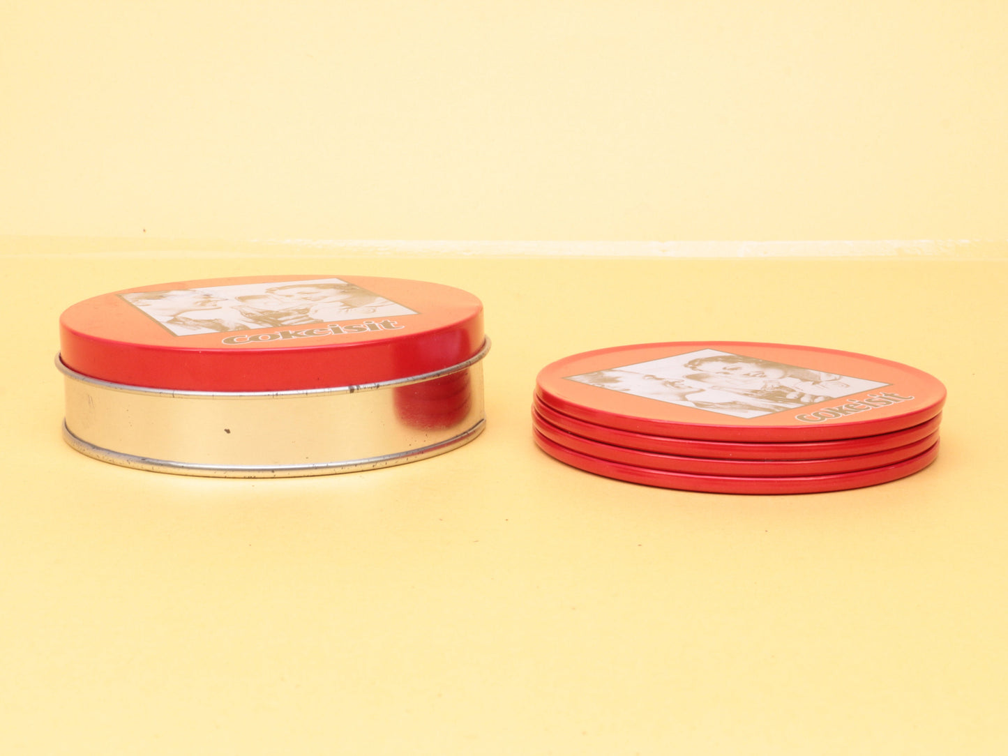 Vintage Coca Cola Set van 4 metalen onderzetters in een bewaarblik, met tekst CokeItIs